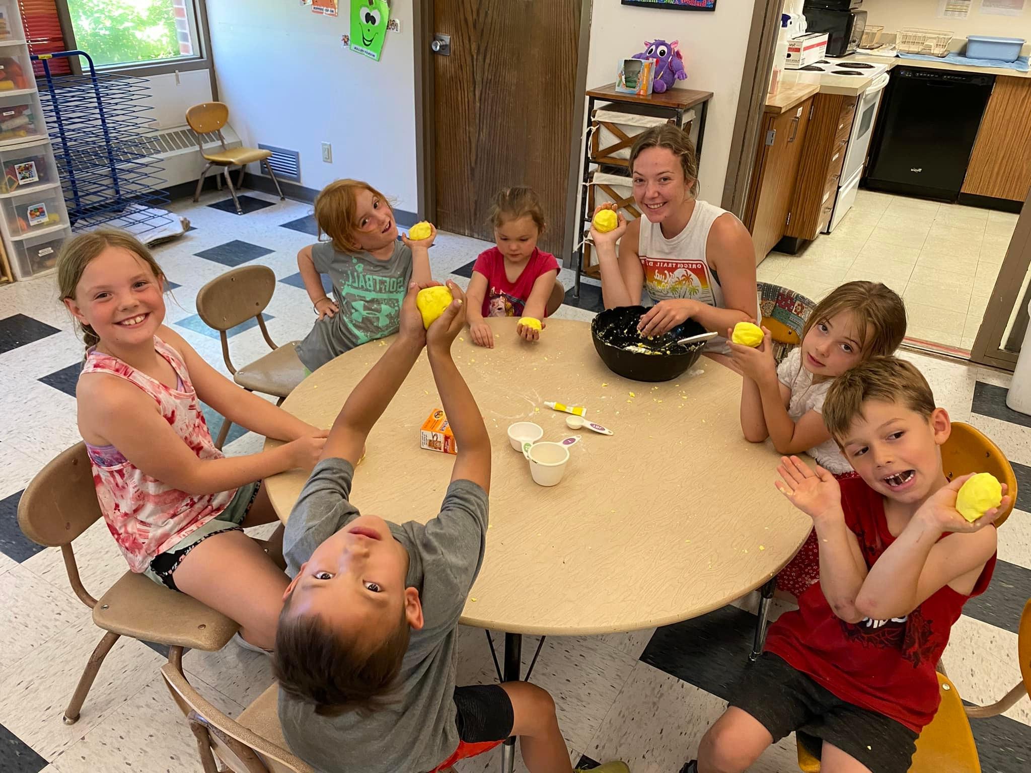 A group of children and a student volunteer smile at the Child Development Center