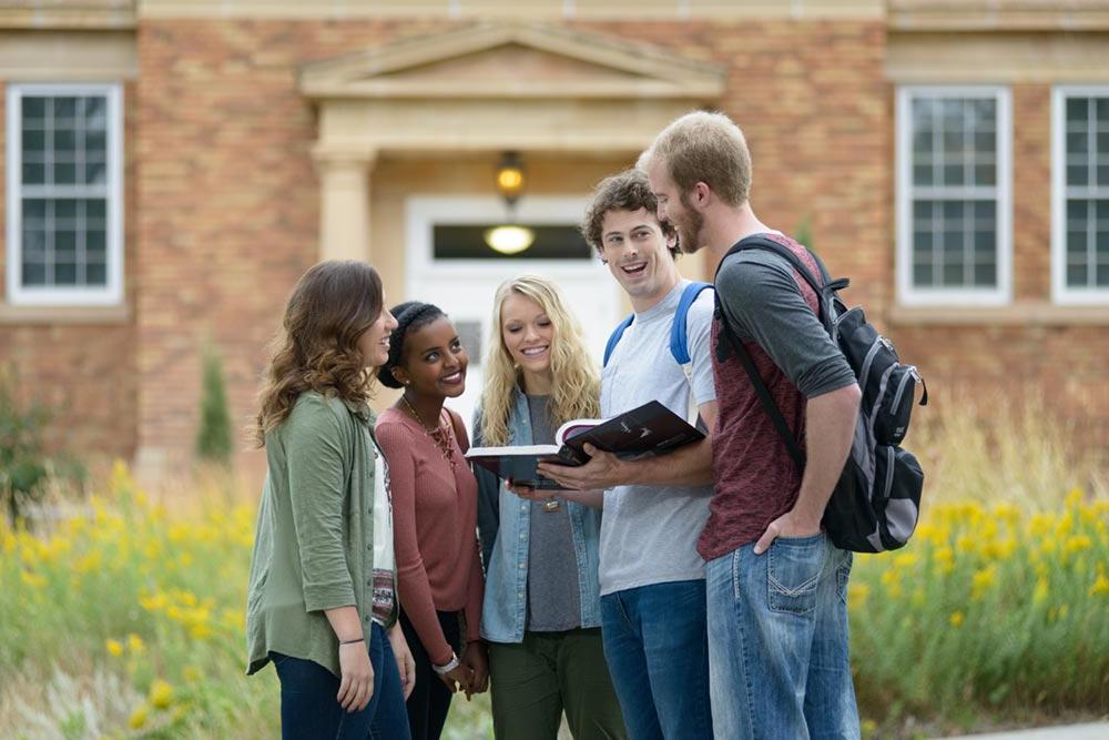 Five students discussing a section of a textbook in front of the Mari Sandoz High Plains Heritage Center